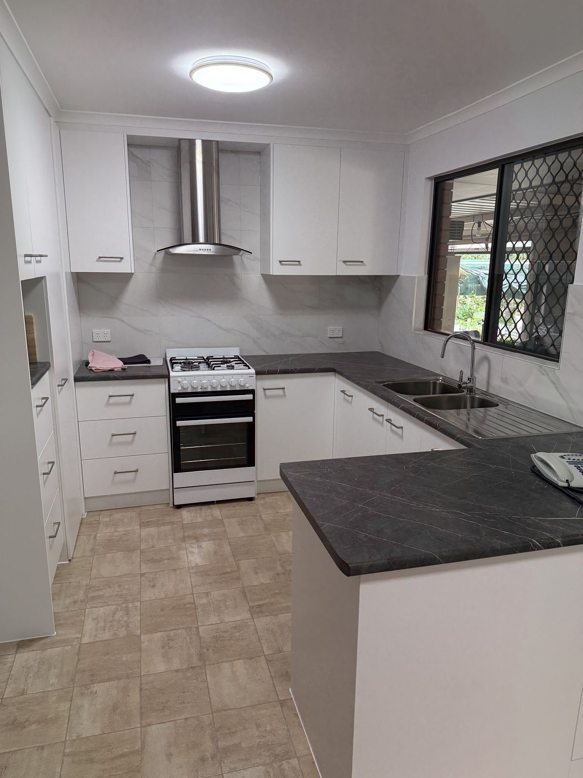 Fully renovated kitchen with stone benchtops, new appliances and tiled splashback
